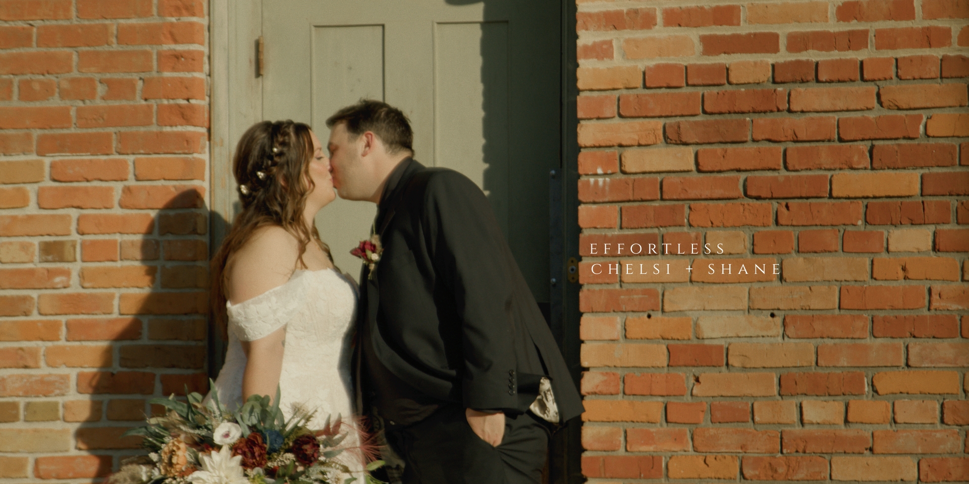 wedding couple kissing in front of vintage door and brick wall